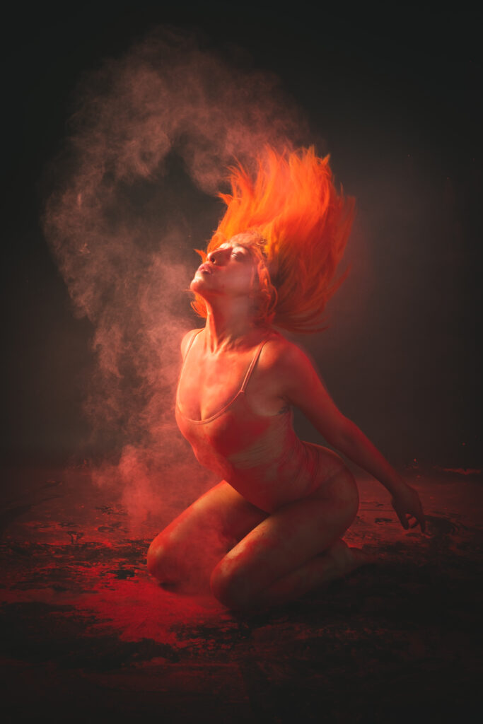 About A vibrant performance artist surrounded by colorful powder and dynamic lighting, creating a striking visual effect.